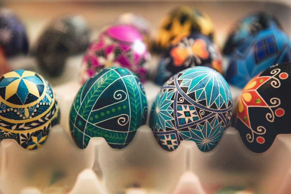 Colorful Ukrainian Easter eggs (pysanky) in a woven basket, decorated with traditional Ukrainian patterns and symbols, including flowers, geometric shapes, and crosses.