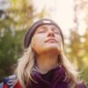 Woman with closed eyes looking up at the sun, symbolizing peace, healing, and resilience.