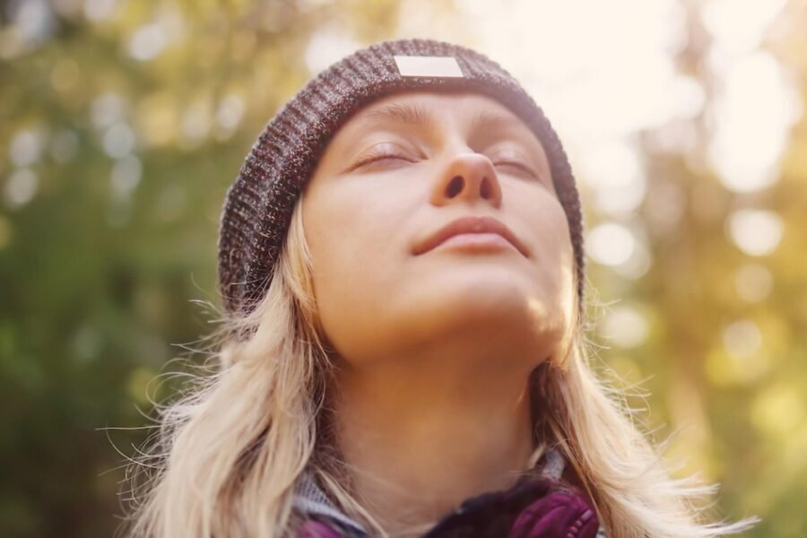 Woman with closed eyes looking up at the sun, symbolizing peace, healing, and resilience.